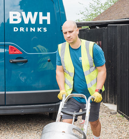 A BWH Drinks driver wheeling a keg from the van