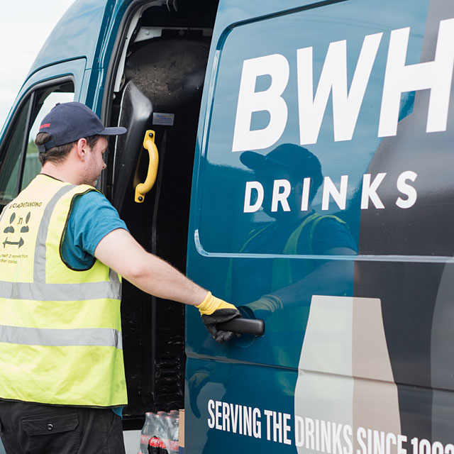 A BWH Drinks delivery driver at the door of a BWH van
