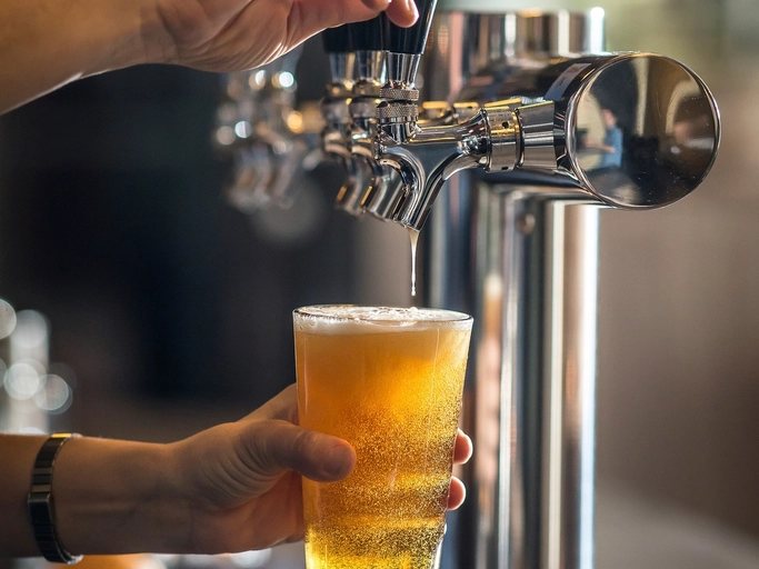 A pint of beer being poured from a tap